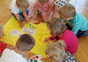 Dzieci robią paluszkowe kropki na kartonie