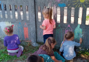 Dzieci malują płot kredą