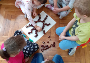 Dzieci układają kasztanowe wzory