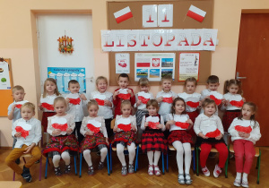 Przedszkolaki w biało - czerwonych strojach trzymają swoje prace.