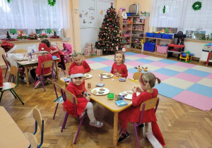 Dzieci przy stolikach dekorują pierniki.