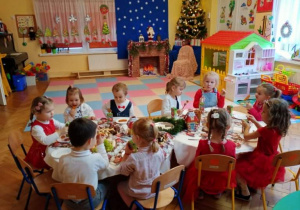 Przedszkolaki siedzą przy świątecznym stole.