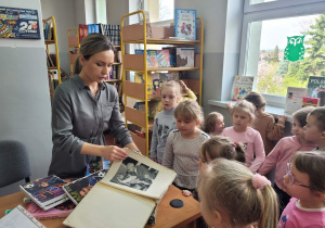 Pani Sylwia pokazuje przedszkolakom ksiązki.