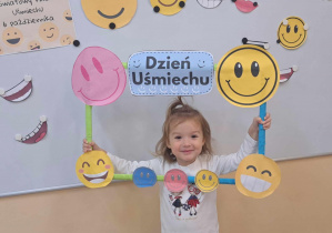 Uśmiechnięta Jagódka trzyma w rękach ramkę z emotkami