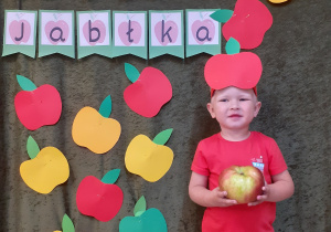 Chłopiec trzyma jabłko w dłoni.