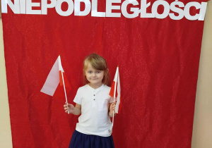 Kornelka trzyma w rękach flagi Polski.