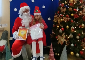 Tosia z mikołajem obok choinki.