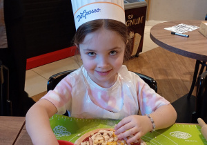 Dziewczynka dodaje składniki do pizzy.