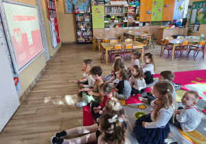 Dzieci oglądają film edukacyjny o barwach i symblach narodowych.